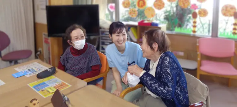 介護施設のレク時間。入居者と職員が机を囲んで交流している風景。